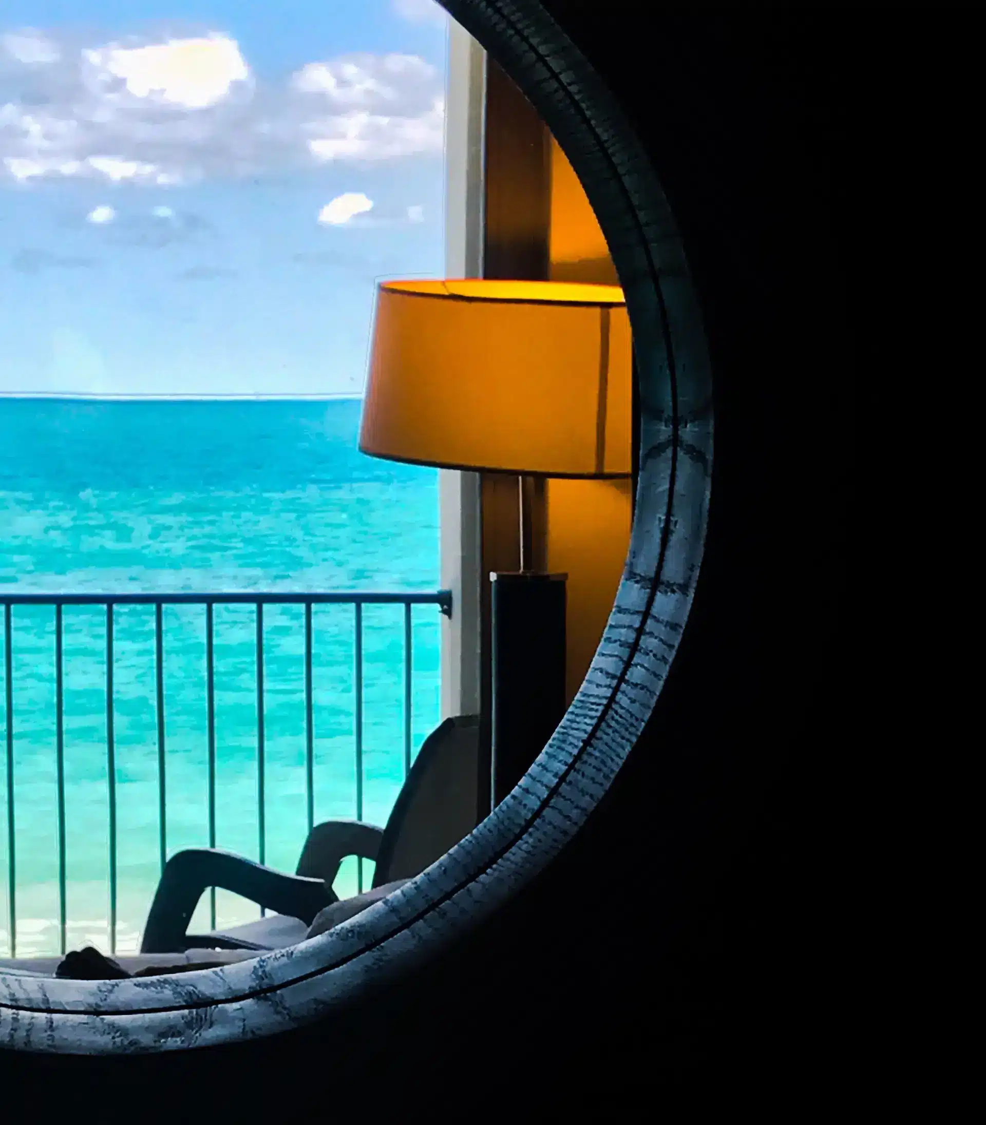A round window with a lamp, looking out to the sea